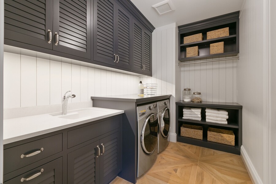 Modern laundry room with sink, front-loading washer and dryer, and storage cabinets